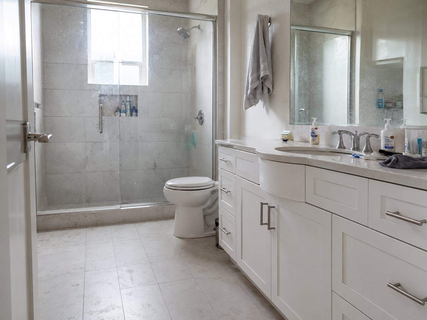 Bathroom before detail cleaning with cloudy shower glass and items on the vanity